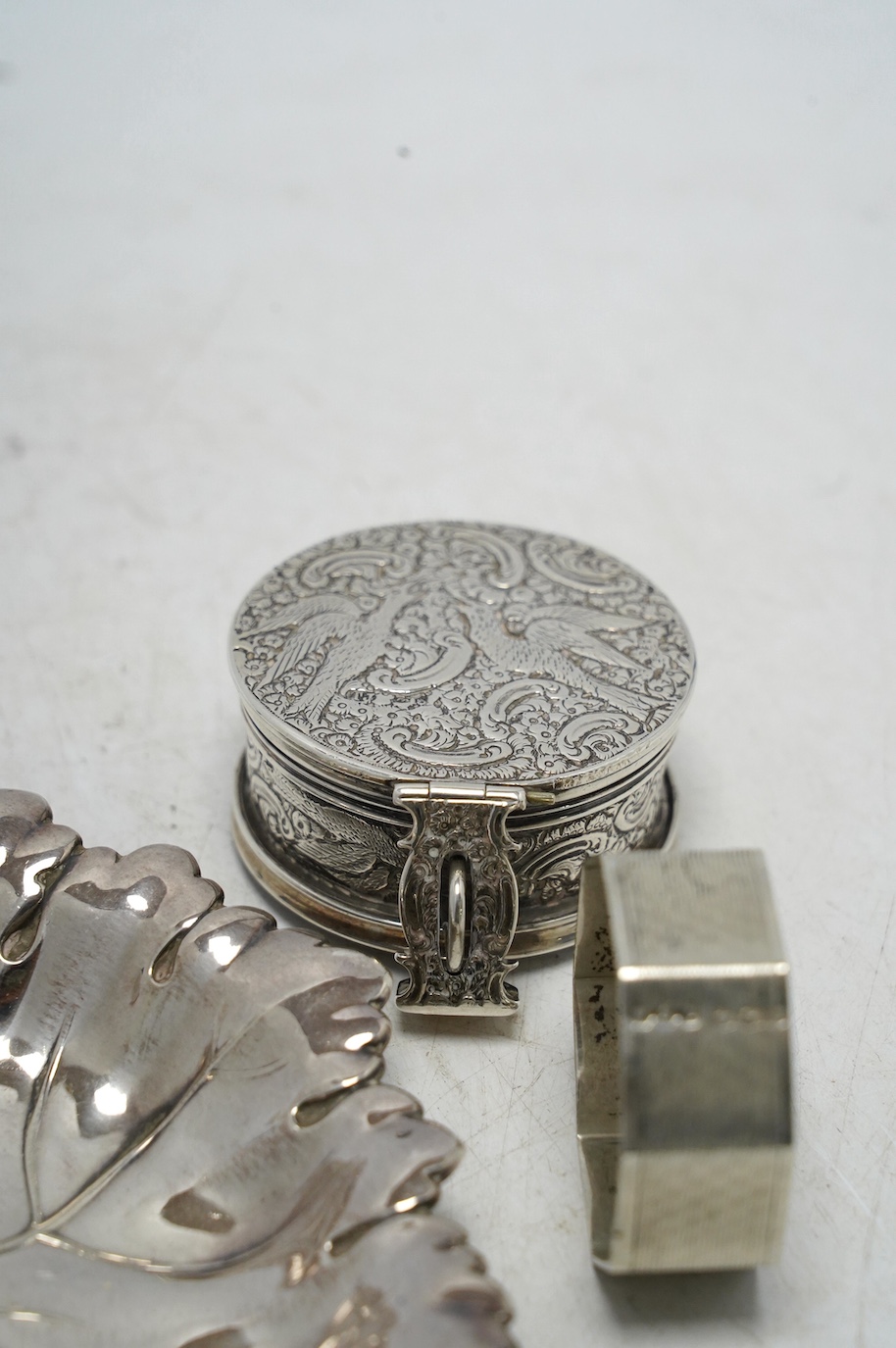 A Victorian silver circular case and cover, containing a collapsible beaker (now detached from the base), by Thomas Johnson I, London, 1873, diameter 53mm, together with a silver napkin ring and modern silver leaf dish.